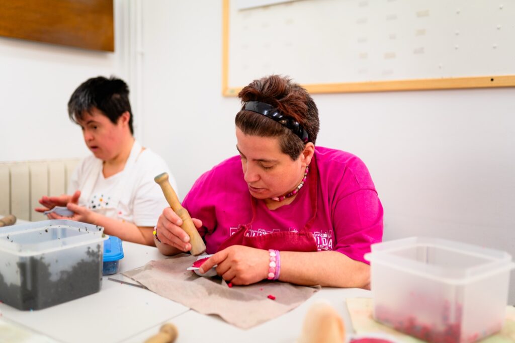 Dues persones del servei d'Inserció laboral fent tasques manuals a una taula